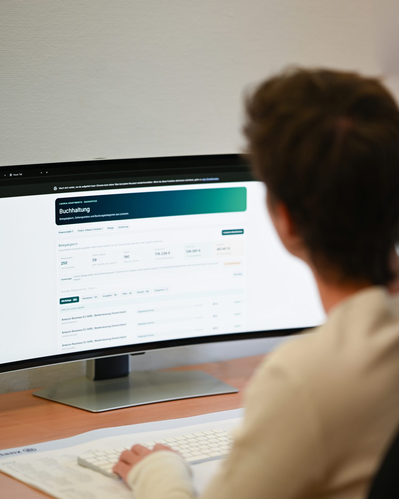 Over-the-shoulder view of a person working at a laptop in the accounting area of the management software